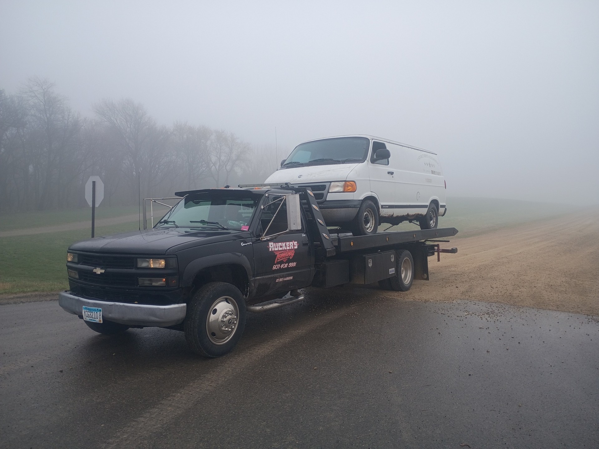 Ruckers Towing hauling a cargo van through morning fog